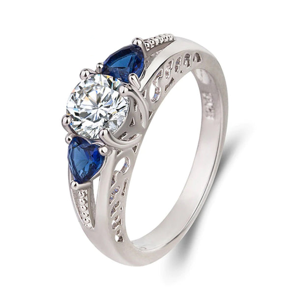 .84 Carat Round Three Stone Ring with Blue Heart Shaped Stones Flanking the Round Center Stone and Accented with Milgrain and Scroll Designs Set in Sterling Silver Eng088