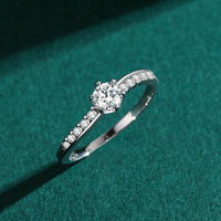 Round engagement ring contoured asymmetrical band and semi channel side stones 